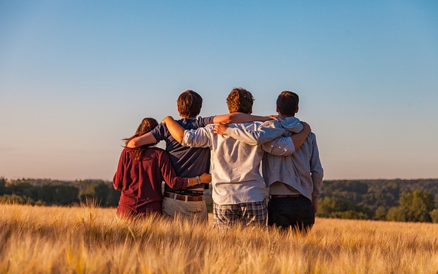 image with a landscape in background and four young people standing together